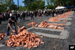 Seorang sukarelawan membantu meletakkan batu bata untuk membangun tungku kremasi di kuil Wat Rat Samakee di Uthai SawanlT. ...... ungku tersebut sedang dibangun pada hari Senin untuk mengkremasi tubuh sebagian besar korban muda dari pembantaian minggu lalu pada satu hari pusat perawatan oleh mantan polisi. (Foto AP/Sakchai Lalit)