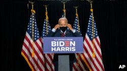 Democratic presidential candidate former Vice President Joe Biden removes his face mask as he arrives to speak at the Hotel DuPont in Wilmington, Del., Aug. 13, 2020. 
