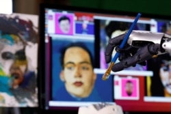 FILE - Humanoid robot Sophia, developed by Hanson Robotics, holds a brush during a demonstration before her non-fungible token (NFT) artwork is auctioned, in Hong Kong, China March 16, 2021. (REUTERS/Tyrone Siu)