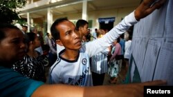 FILE - People look through the voters' list after a polling station opened for the general elections in Kandal province July 28, 2013.