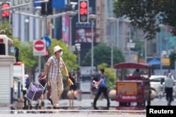 Seorang pria mengenakan masker di tengah peringatan gelombang panas di Shanghai, Cina 13 Juli 2022. (Foto: REUTERS/Aly Song)