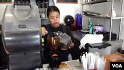 Joy Solayao grinds beans at the Silingan coffee shop near Manila. Solayao, like most employees at the shop, lost a loved one during former Philippines President Rodrigo Duterte's war on drugs. (Dave Grunebaum/VOA)