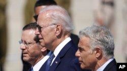 Presiden Joe Biden, tengah, Presiden Israel Isaac Herzog, kiri, dan Perdana Menteri Israel Yair Lapid, berjalan saat upacara penyambutan ketika Biden tiba di Bandara Ben Gurion, dekat Tel Aviv, Israel, Rabu, 13 Juli 2022. (Foto: AP )