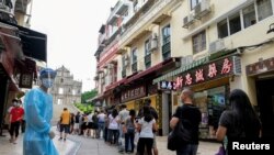 FILE - People line up to be tested for the coronavirus that causes COVID-19 near the Ruins of Saint Paul's in Macao, China, June 20, 2022.