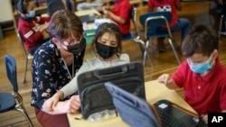 Kindergarten teacher Karen Drolet, left, works with a student at Raices Dual Language Academy, a public school in Central Falls, R.I., Feb. 9, 2022. (AP Photo/David Goldman, File)