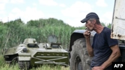 A farmer uses a tractor to tow an armored personnel carrier abandoned by Russian troops and commandeered by a Ukrainian farmer at the end of March, near the village of Mala Rogan, Kharkiv region, on July 28, 2022.