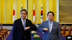 South Korean Foreign Minister Park Jin, left, and Japanese counterpart Yoshimasa Hayashi pose for a photo as they bump elbows to greet each other before their talks in Tokyo, July 18, 2022.