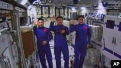 Tangkapan layar dari Pusat Kontrol Dirgantara Beijing, menunjukkan astronot China dari kiri, Cai Xuzhe, Chen Dong dan Liu Yang melambai dari dalam modul lab antariksa China "Wentian" pada Senin, 25 Juli 2022 (foto: dok). 
