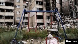 A teddy bear is seen next to a swing, next to buildings destroyed by military strikes, as Russia's invasion of Ukraine continues, in Saltivka, one of the most damaged residential areas of Kharkiv, July 17, 2022. 