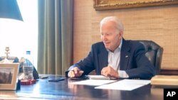 In this image provided by the White House, President Joe Biden speaks on the phone from the Treaty Room in the residence of the White House, July 21, 2022. Biden says he's "doing great" after testing positive for COVID-19. 