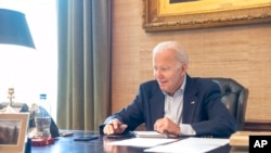 In this image provided by the White House, President Joe Biden speaks on the phone from the Treaty Room in the residence of the White House, July 21, 2022. Biden says he's "doing great" after testing positive for COVID-19. 