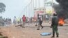 Un policier regarde des manifestants bloquer des routes et lancer des pierres à Conakry le 28 juillet 2022, après que les autorités ont empêché les partisans du parti d'opposition, le Front national pour la défense de la Constitution (FNDC), de se rassembler.