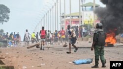 Un policier regarde des manifestants bloquer des routes et lancer des pierres à Conakry le 28 juillet 2022, après que les autorités ont empêché les partisans du parti d'opposition, le Front national pour la défense de la Constitution (FNDC), de se rassembler.