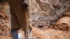 Un homme tenant une pioche observe des collègues travaillant dans un puits ouvert de la mine de coltan SMB près de la ville de Rubaya, dans l'est de la République démocratique du Congo, le 13 août 2019. Photo prise le 13 août 2019. REUTERS/Baz Ratner