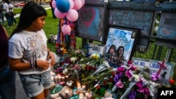 资料照片：一名女孩站在德克萨斯州尤瓦尔迪市法院外的纪念场地，几天前该市的罗伯小学发生了导致21人死亡的大规模枪击案。(2022年5月28日)