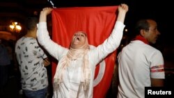 A woman holding a flag celebrates after exit poll indicates voters backed new constitution in Tunis, Tunisia, July 25, 2022.