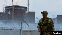 سربازی که روی اونیفرمش پرچم روسیه نقش بسته در نزییکی نیروگاه هسته‌ای زاپوریژیا نگهبانی می‌دهد (۱۳ مرداد ۱۴۰۱) 