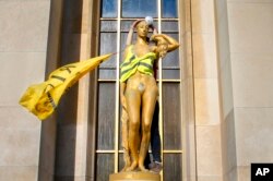 A demonstrator places a mask and a yellow vest on a statue titled "Le Matin," or "The Morning," as French "yellow vest" protesters rally in support of a fellow activist who was injured in a recent confrontation with police, March 30, 2019, in Trocadero Square, Paris.