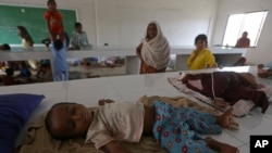 Displaced families take refuge in a government college building after fleeing their flood-hit homes, in Karachi, Pakistan, Aug. 29, 2022.
