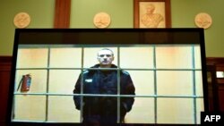 Pemimpin oposisi Alexei Navalny muncul di layar yang dipasang di ruang sidang Pengadilan Kota Moskow melalui tautan video dari koloni penjaranya di Moskow pada 24 Mei 2022. (Foto: AFP)