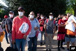 Migrants hold Red Cross blankets after arriving at Union Station near the U.S. Capitol from Texas on buses, April 27, 2022, in Washington. (AP Photo/Jose Luis Magana, File)