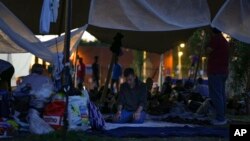 A man prays under a tarpaulin as hundreds of migrants who seek shelter prepared to spend the night outside an overcrowded asylum seekers center in Ter Apel, northern Netherlands, Aug. 25, 2022.