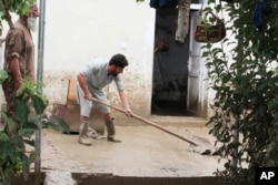 People clean up their damaged homes after heavy flooding in the Khushi district of Logar province south of Kabul, Afghanistan, Sunday, Aug. 21, 2022.