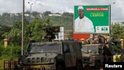 FILE - A convoy of peace keeping forces stand next to an electoral billboard of Soumaila Cisse, leader of URD (Union for the Republic and Democracy) opposition party during a patrol in Bamako, Mali, Aug. 9, 2018. 