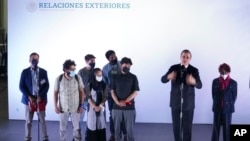 FILE - Afghan journalist refugees stand during a welcoming ceremony by Mexican Foreign Minister Marcelo Ebrard, speaking, upon arrival to Benito Juarez International Airport in Mexico City, Aug. 25, 2021.