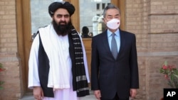 FILE - In this photo released by Xinhua News Agency, Chinese Foreign Minister Wang Yi poses for photos with Amir Khan Muttaqi, acting foreign minister of the Afghan Taliban's caretaker government, in Kabul, March 24, 2022. (Saifurahman Safi/Xinhua via AP)