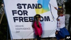 Children play near a banner during a ceremony to mark Ukraine's Independence Day, in Lisbon, Portugal, Aug. 24, 2022. Portugal is home to a large community of emigres from Ukraine, and has taken in tens of thousands of refugees from the country since late February.