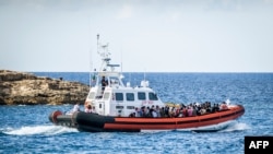 Les migrants à bord d'un navire militaire de la Guradia di Finanza et de la marine sont transférés de l'installation de traitement opérationnel dite "Hotspot" des migrants sur l'île méridionale italienne de Lampedusa, au sud de la Sicile, vers un autre centre, le 11 juillet 2022.