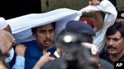 Police officers escort Shahbaz Gill, center in blue shirt, a political aide to former Pakistani prime minister Imran Khan, after a court appearance, in Islamabad, Aug. 22, 2022.