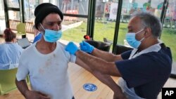 A doctor administers a COVID-19 vaccine to a homeless person in Ilford, east London, Feb. 5, 2021. A study found that people in the poorest regions of England are diagnosed with serious illnesses earlier and die sooner than their counterparts in more affl