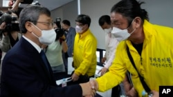 FILE - Truth and Reconciliation Commission's chairperson Jung Geun-sik, left, shakes hands with Choi Seung-woo, a victim of Brothers Home, during a press conference at the commission's office in Seoul, South Korea, Aug. 24, 2022. 