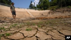 Gan Bingdong stands in a dried out community reservoir near his farm in Longquan village in southwestern China's Chongqing municipality on Aug. 20, 2022. (AP Photo/Mark Schiefelbein)