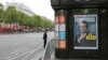 A police officer stands guard next to a newsstand displaying the cover of a news magazine depicting French president-elect Emmanuel Macron on the Champs Elyses avenue in Paris, France, May 8, 2017. 