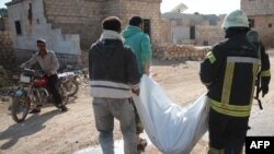 Members of the Syrian Civil Defense, also known as the White Helmets, walk with a body bag of a victim of a reported airstrike in the Syrian village of al-Sahharah in the countryside west of the northern city of Aleppo, Nov. 6, 2019.
