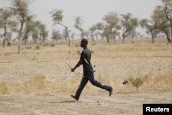 FILE - A member of a civilian vigilante group carries a bow and arrow while running on patrol with the Cameroonian military in Kerawa, Cameroon, March 16, 2016. Kerawa is on the border with Nigeria and is subject to frequent Boko Haram attacks.