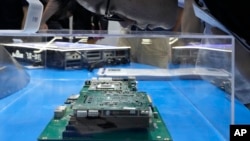 A visitor examines a computer chipset at the booth for Chinese semiconductor and chip developer Kunlunxin during the World AI Conference in Shanghai, Wednesday, July 5, 2023. (AP Photo/Ng Han Guan)
