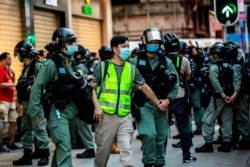FILE - Police arrest a man and lead him to a nearby bus during a protest against China's planned national security law in Hong Kong on June 28, 2020.