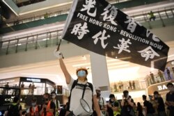 A pro-democracy activist waves a banner during a protest at the New Town Plaza mall in Hong Kong, June 12, 2020.