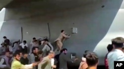 Hundreds of people run alongside a U.S. Air Force C-17 transport plane, some climbing on the plane, as it moves down a runway of the international airport, in Kabul, Afghanistan, Aug.16. 2021.