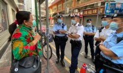 住在佐敦封鎖區內的尼泊爾籍居民Rai在社區封鎖前離家上班，她下班返家才知道當局已經實施封區禁足強制檢測，她向在場駐守的警員查詢如何返回封鎖區內。（美國之音 湯惠芸拍攝）