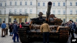 In this file image, a man looks at a destroyed Russian tank placed as a symbol of war in downtown Kyiv, Ukraine, May 23, 2022. (AP Photo/Natacha Pisarenko, File)
