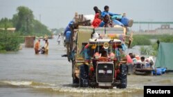 A family puts their belongings on a higher ground as they travel, following rains and floods during the monsoon season in Sohbatpur, Pakistan, Aug. 29, 2022.