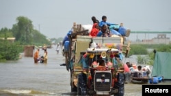 Satu keluarga mengungsi sambil membawa barang-barang milik mereka yang masih dapat diselamatkan di tengah hujan deras dan banjir yang melanda wilayah Sohbatpur, Pakistan, pada 29 Agustus 2022. (Foto: Reuters/Amer Hussain)