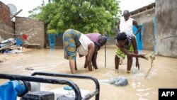 Des habitants du quartier d'Amtoukiou creusent un trou pour pomper l'eau de la cour de la maison de NDjamena, le 5 août 2022.