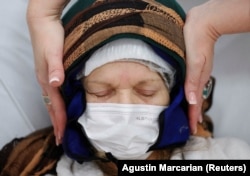 Seorang teman menghibur pasien kanker Elsa Ram yang mengenakan helm darurat dari kantong es yang mencegah kerontokan rambut, selama sesi kemoterapi, di Buenos Aires, Argentina, 4 Agustus 2022. (Foto: REUTERS/Agustin Marcarian)