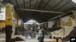 Porceus Vethal and her daughter walk past the ruins of the Saint-Helene chapel destroyed by last year's 7.2-magnitude earthquake, in the area of Labore in Les Cayes, Haiti, Aug. 18, 2022.